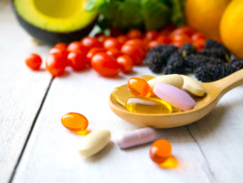 Pills and capsules in wooden spoon with fresh fruits.Multivitamins and supplement from fruits concept.